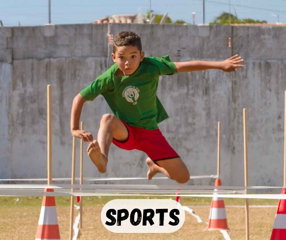 boy jumping over hurdle in field at cbc